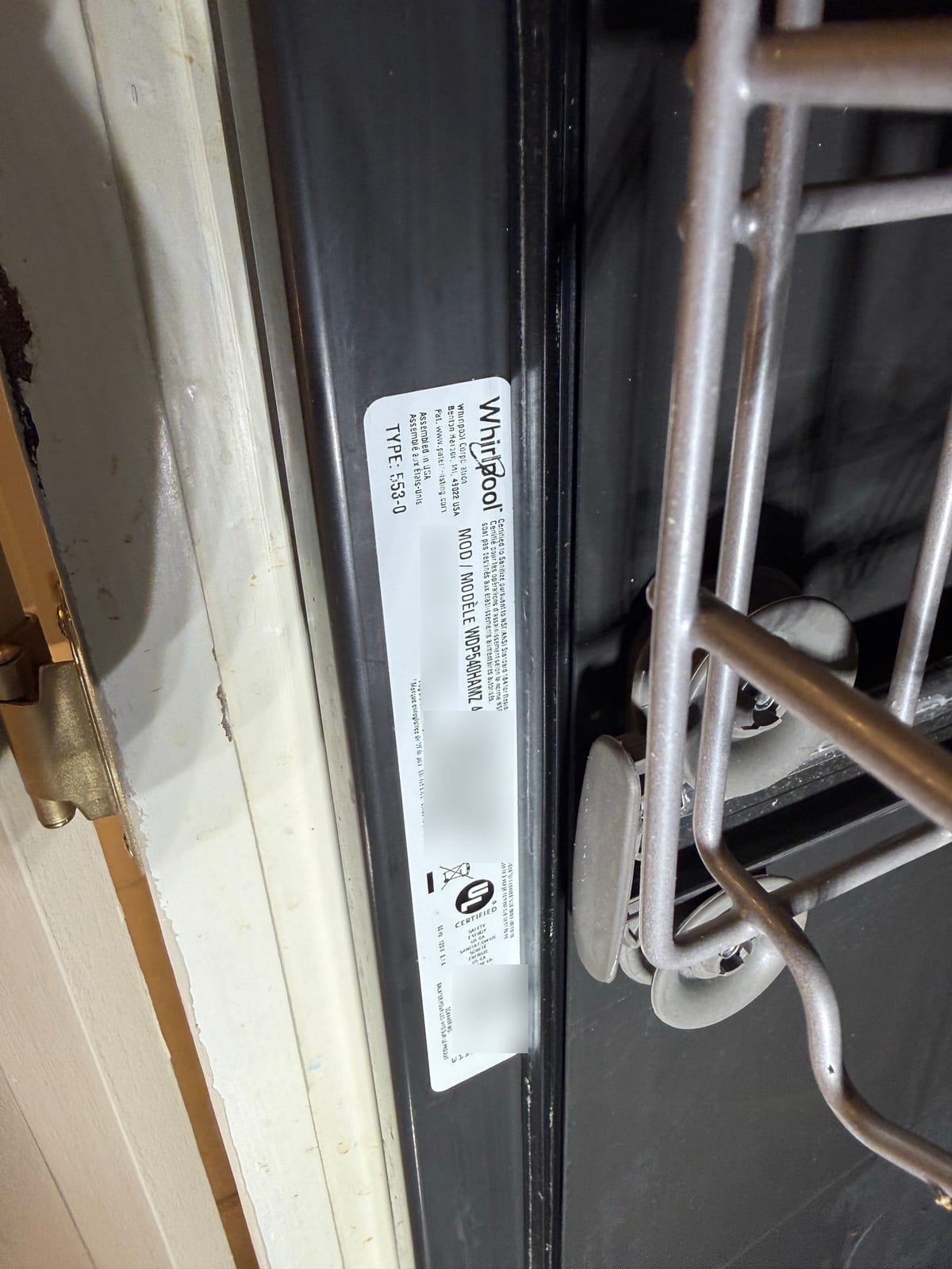 Whirlpool dishwasher data label with the model number readable; serial number, barcodes and QR code blurred