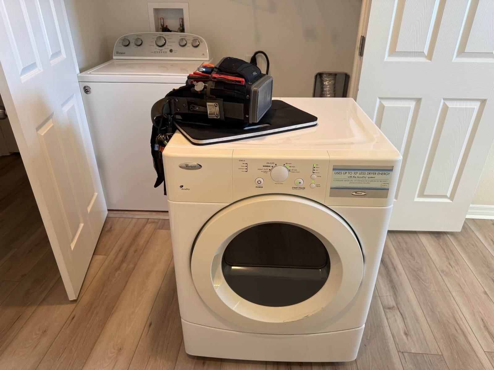 Whirlpool dryer reassembled and powered on with the control panel lit, our tool bag on top