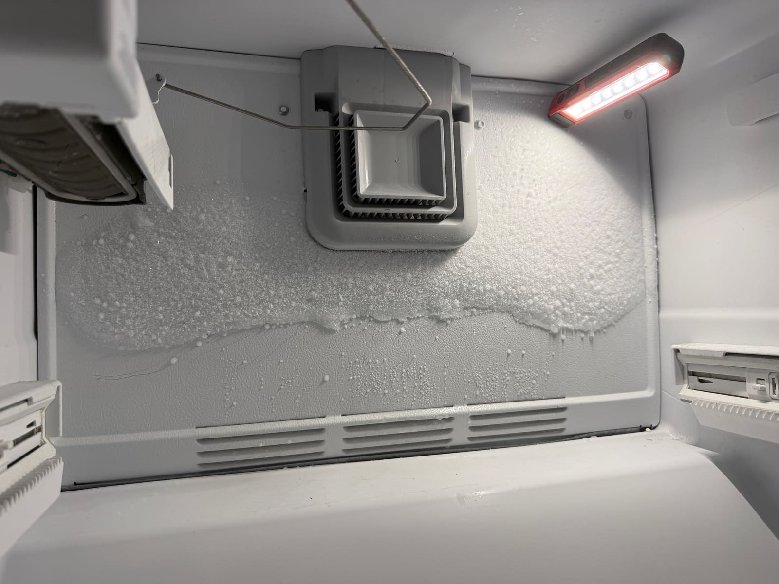 Frost covering the evaporator cover at the back of the Whirlpool freezer, with the ice maker at the top left