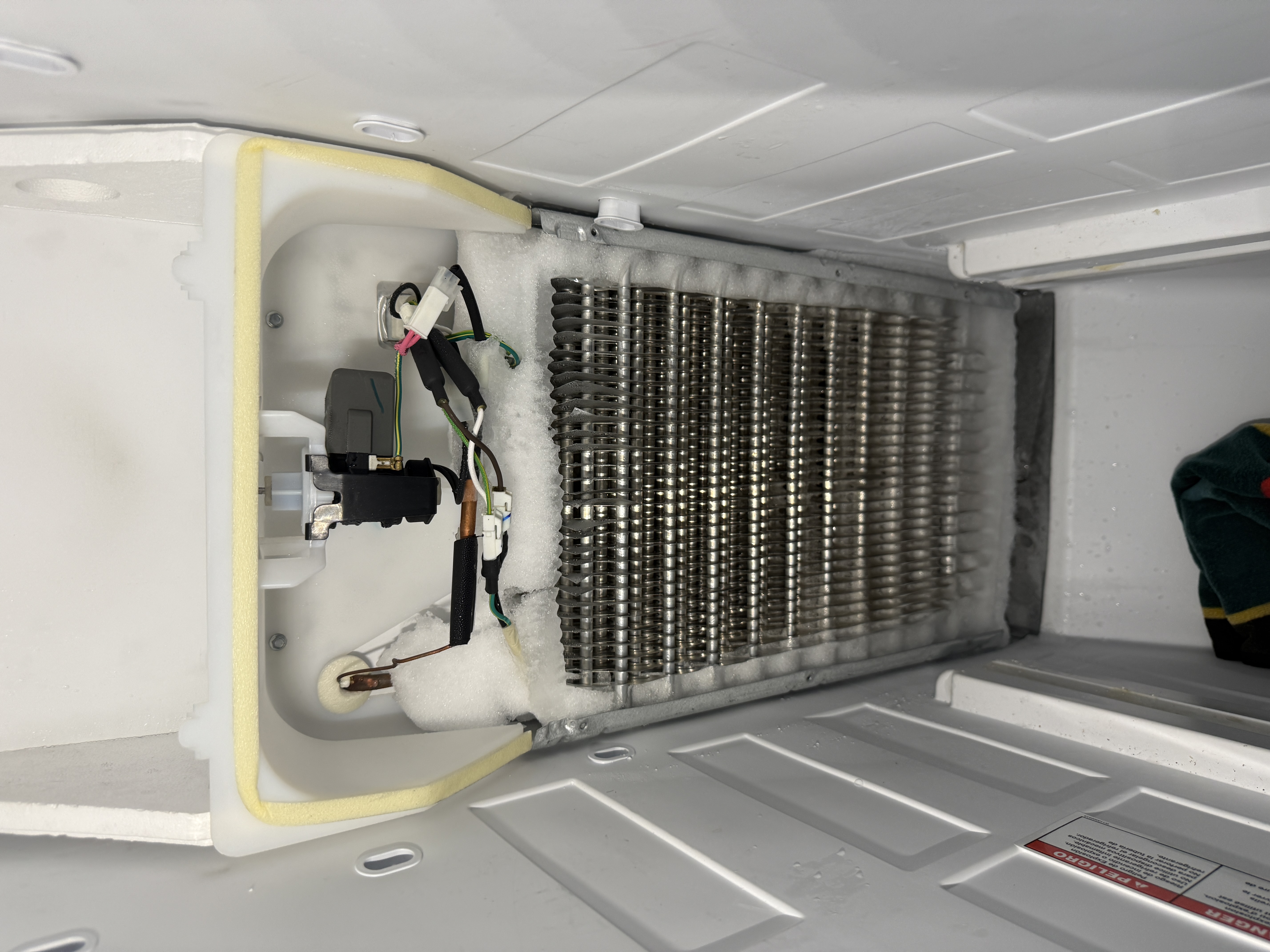 Fully frozen evaporator coil inside a Whirlpool refrigerator's freezer section