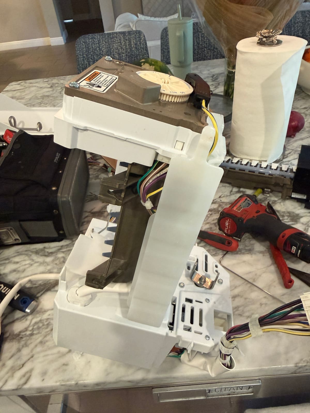 New Whirlpool ice maker with its tan control head mounted in the ice maker housing before going back into the refrigerator
