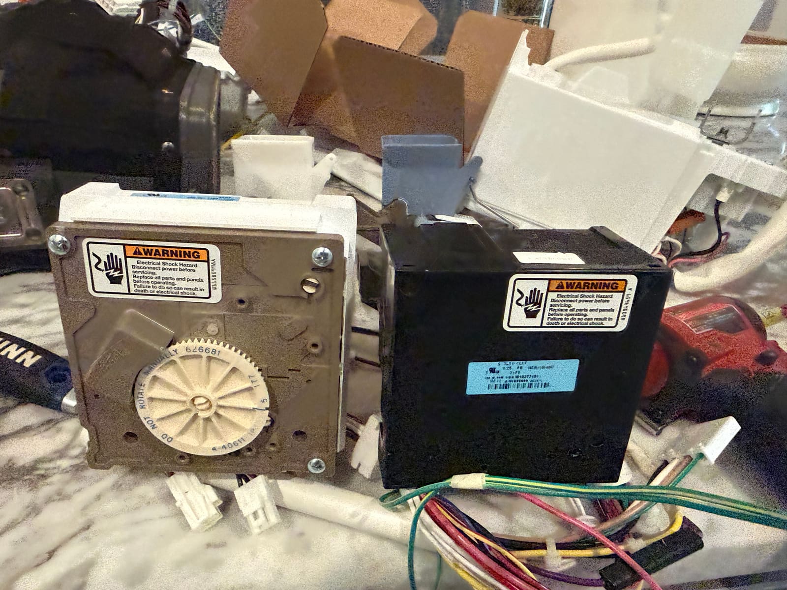 New ice maker's tan gear-driven control head on the left next to the old ice maker's black electronic control module on the right