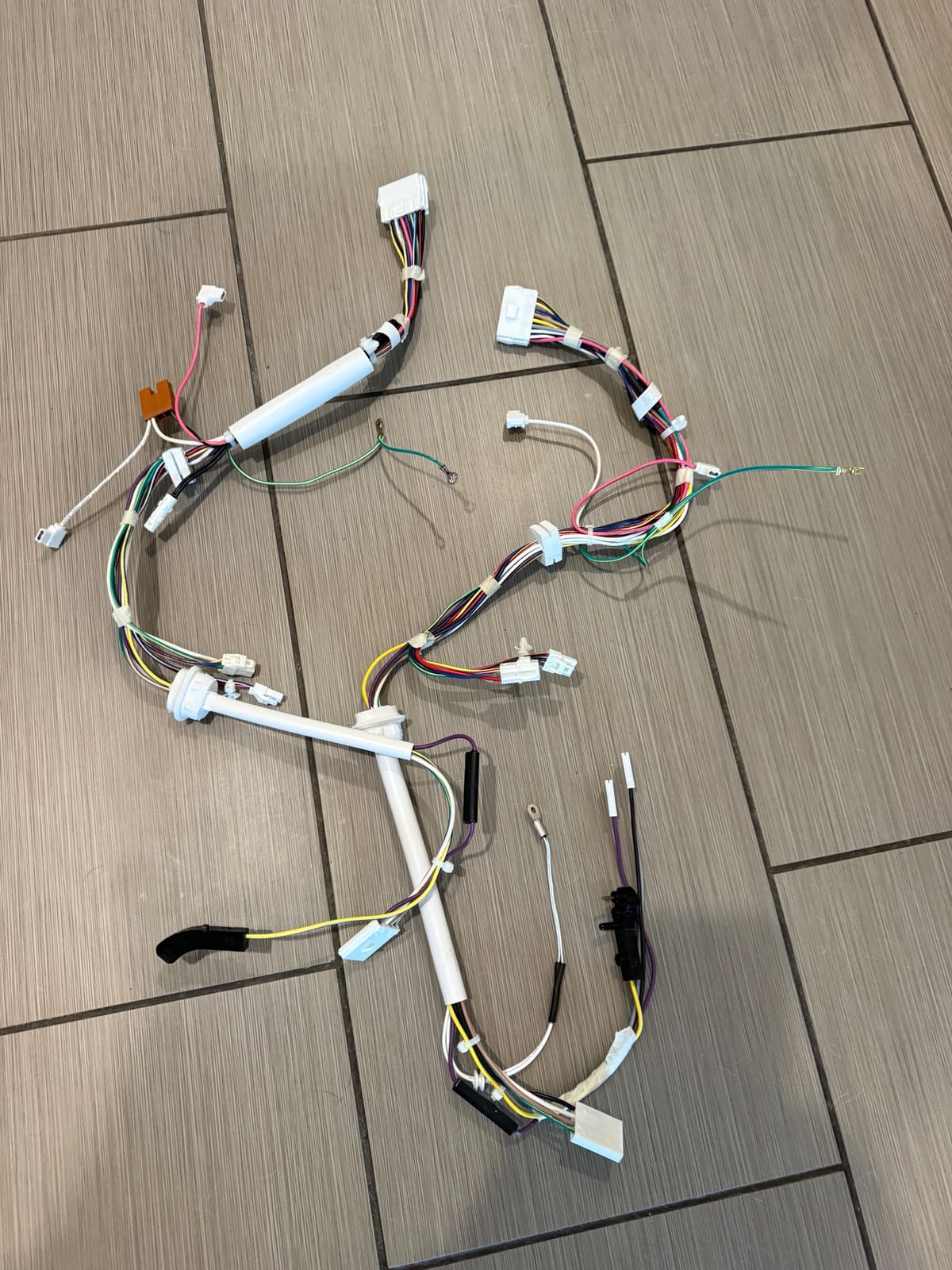 New wire harnesses from the Whirlpool W10882923 ice maker kit laid out on a tile floor