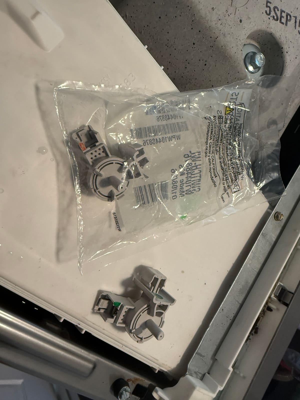 New Whirlpool pressure switch in its bag next to the old pressure switch