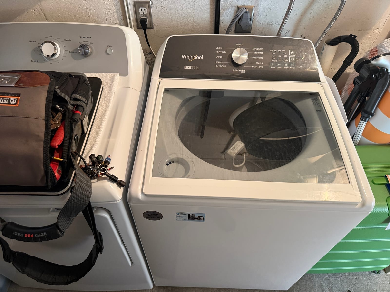 Whirlpool top-load washer next to a dryer in a garage laundry area at the Cove complex in Clearwater