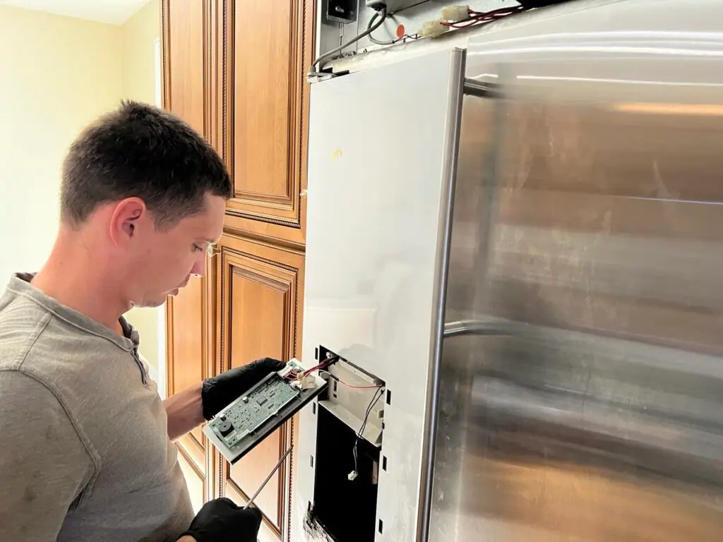 Technician repairing a refrigerator in Palm Harbor home